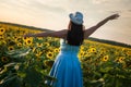 Big size Girl model in a blue dress leaves with hat in field of sunflowers on the sunset. Follow me concept Royalty Free Stock Photo