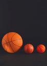 Big and small basketball balls on black background