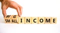 Big or small income symbol. Businessman turns wooden cubes and changes words Small income to Big income. Beautiful white table