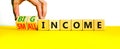 Big or small income symbol. Businessman turns wooden cubes and changes words Small income to Big income. Beautiful yellow table