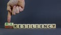 Big or small resiliency symbol. Businessman turns wooden cubes, changes words small resiliency to big resiliency. Beautiful grey