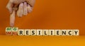 Big or small resiliency symbol. Businessman turns wooden cubes, changes words small resiliency to big resiliency. Beautiful orange