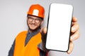 Big smartphone with blank on screen in hand on construction worker, smiling man. Close-up view. Mock up concept. White background