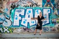 Big smile of an elegant lady in front of a wall with graffiti. A wall vandalized with street graffiti art.