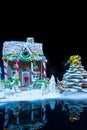 Big snow-covered homemade gingerbread house, gingerbread Christmas tree and a sugar mastic snowman on dark background Royalty Free Stock Photo