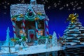 Big snow-covered homemade gingerbread house with lights inside,