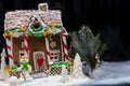 Big snow-covered homemade gingerbread house, a sprig of Christmas tree and a sugar mastic snowman on dark background Royalty Free Stock Photo