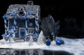 Big snow-covered homemade gingerbread house, a sprig of Christmas tree and a sugar mastic snowman in white and blue tones on dark Royalty Free Stock Photo