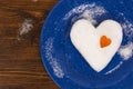 The big snow heart decorated with small orange heart lying on blue plate.