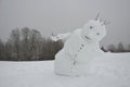 A big snowman has a sloping body that looks like he is falling, not limping, and has back pain. going away the winter is over. for