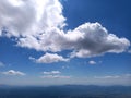 Big soft clouds on the blue sky in summer, below are the mountains Royalty Free Stock Photo