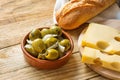 Big Spanish Green Gordal Olives with Herbs and Onions in Earthenware Bowl Baguette Maasdam Cheese on Cutting Board Royalty Free Stock Photo