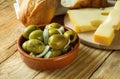 Big Spanish Green Gordal Olives with Herbs and Onions in Earthenware Bowl Sliced Baguette Maasdam Cheese on Cutting Board