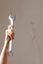 Big spanner in the woman`s hand. hand holds a wrench on a gray background. Combination wrench. big chrome vanadium spanner in the Royalty Free Stock Photo