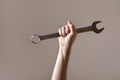 Big spanner in the woman`s hand. hand holds a wrench on a gray background. Combination wrench. big chrome vanadium spanner in the Royalty Free Stock Photo