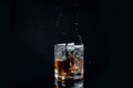 Whiskey splash from the fallen ice cube into glass with beverage isolated on black background Royalty Free Stock Photo