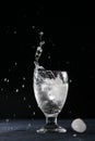 Big splash in a glass of clear cold water tempting for a drink. Isolated on black