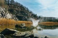 Big splash in swamped quarry with high dry grass, small pond, rock, Czech republic