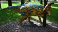 Big statue of colorful painted Parasaurolophus dinosaur in a forest