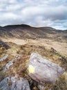 Big stone with sign and three people hiking in mountins in Gleninchaquin park