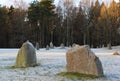 The big stones standing in the snow field in winter