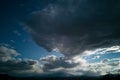 big stormy clouds in the blue sky and sun rays over the mountains in a winter day