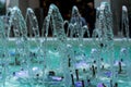 Big and strong water jets from the fountain with blue illumination in shopping center. Splashes and drops. Royalty Free Stock Photo