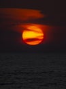 Big sun with black clouds, making a dark orange sunset background.