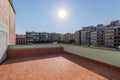 Big sunny terrace on the roof of modern building lined with red brick tiles overlooking the neighboring houses. Summer