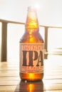 Lagunitas IPA India Pale Ale beer bottle against strong sunlight. Wooden table Royalty Free Stock Photo