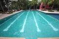 A big swimming pool with clear water and seats in water in the Nong Nooch tropical botanic garden near Pattaya city in Thailand