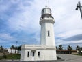 Big tall stone white lighthouse on the tropical sea warm summer resort with palm trees against the blue sky Royalty Free Stock Photo