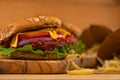 Big tasty burger with beef, tomato, lettuce, red onion, cheese, mustard and ketchup on wooden chopped board with french potato. Royalty Free Stock Photo