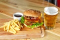 Big tasty burger and fries with beer on backround on the wooden table Royalty Free Stock Photo