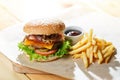 Big tasty burger and fries on the wooden table Royalty Free Stock Photo