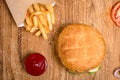 Big tasty cheeseburger on the wooden table with french fries. Delicious lunch with cheese, tomatoos and salad. Fast food with beer