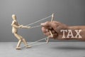 Big tax restrains business development as a puppeteer doll. The hand of the puppeteer is holding a scared wooden doll
