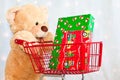 Big teddy bear with shopping cart and presents Royalty Free Stock Photo