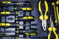 Big tool kit of black and yellow colors for the house in a box. Flat-nose pliers, screw-drivers, stationery knife and nippers. Royalty Free Stock Photo