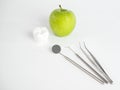 Big tooth and dentist mirror in the dentist clinic in front of the white background with a green apple Royalty Free Stock Photo