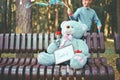 Big toy bear sitting on a bench and holding a red rose and a frame for a photo with the inscription comfort. concept of