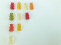 Big triangle ladder made of beautiful sweet delicious multicolored chewy bears juicy fruit gummy candies on a white background