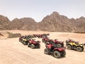 The big turn is a lot of four-wheeled multi-colored powerful fast off-road all-wheel drive ATVs, motorcycles in the sandy hot dese Royalty Free Stock Photo