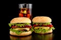 Big two cheeseburgers with glass of cola on black wooden table Royalty Free Stock Photo