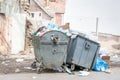 Big two metal dumpster garbage can full of overflow litter polluting the street in the city