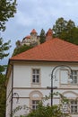 Big two-storied residential building with red tile roof. Famous Bled Castle at the cliff in the background.
