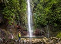 Big waterfall and woman hiker at levada 25 fountains in Rabacal, Madeira island