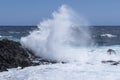 a big wave breaks against some rocks on the seashore, on a rough sea day, foam from the waves on the blue ocean, powerful splash Royalty Free Stock Photo