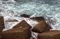 Big waves in the sea at the stone block jetty. Sea pier with breakwater stone cubes close-up view. The Tyrrhenian Sea, Cefalu,