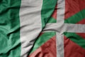 big waving national colorful flag of basque country and national flag of nigeria Royalty Free Stock Photo